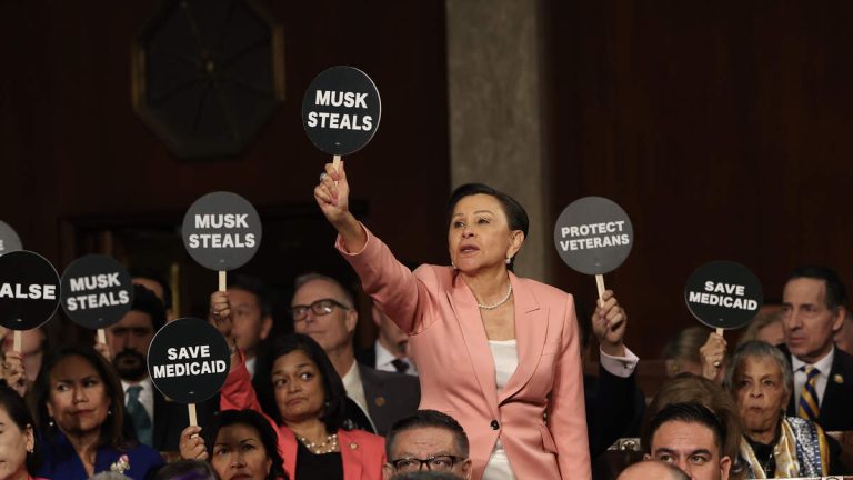 Progressive Lawmakers Hold Up Protest Signs During President Trump’s Speech
